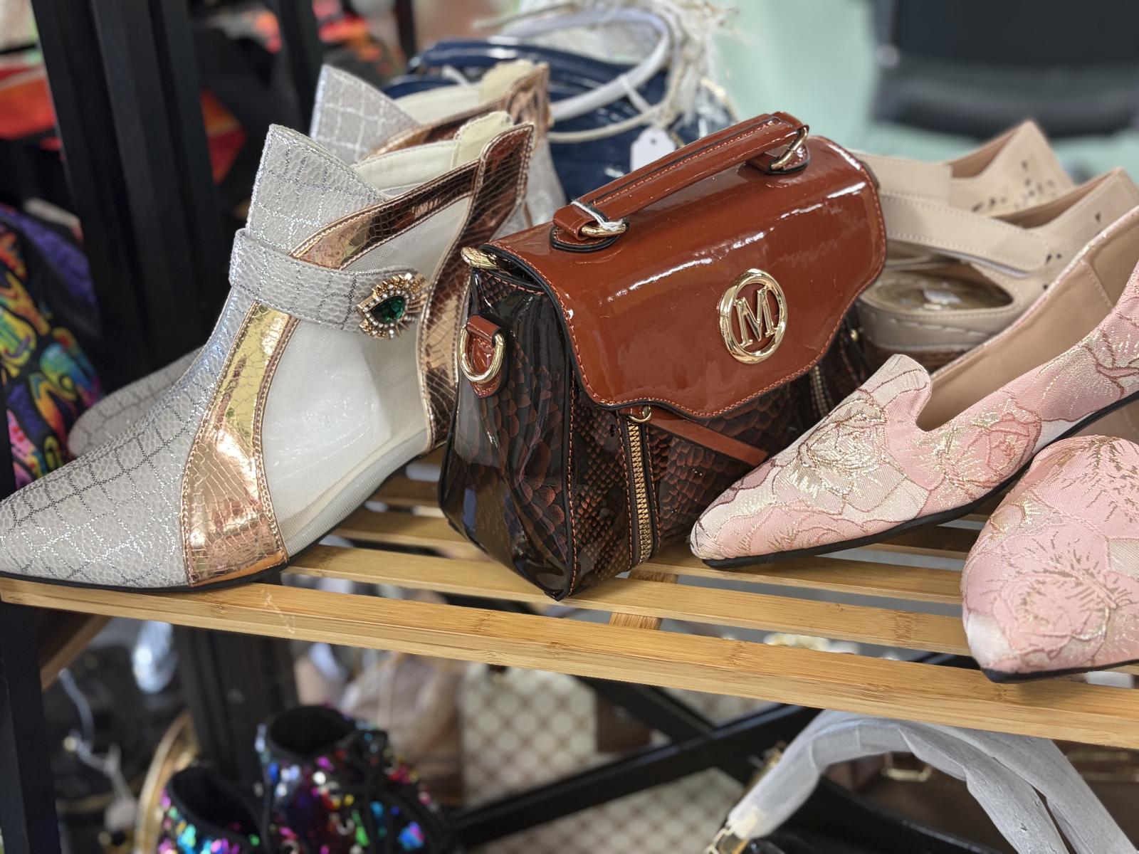 Metallic ankle boots, pink floral shoes and a brown handbag on display
